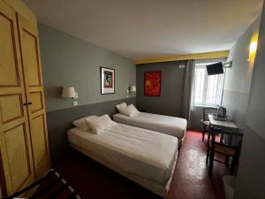 um quarto de hotel com duas camas e uma mesa e uma janela em Le Vieux Château em Aiguines