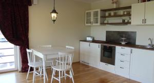 a kitchen with white cabinets and a table and chairs at Kotkapoja Residence in Kuressaare