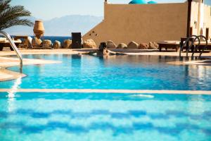 a person laying in a swimming pool with blue water at The Bedouin Moon in Dahab