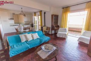 ein Wohnzimmer mit einem blauen Sofa und einem Tisch in der Unterkunft Appartamento Maria Teresa in Porto Santo Stefano