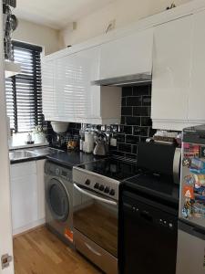 uma cozinha com um fogão e uma máquina de lavar louça em Lovely 2-bedroom apartment in Zone 2 London em Londres