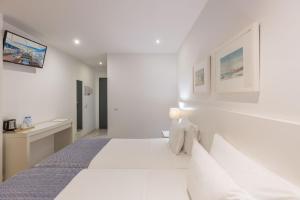 a white bedroom with a bed and a desk at Hotel Baltum in Albufeira