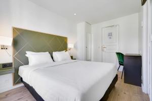 uma grande cama branca num quarto de hotel em Hotel B Square em Paris