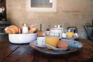 einem Holztisch mit einem Teller Eier und Orangensaft in der Unterkunft L’échappée Vendéenne in Saint-Aubin-la-Plaine