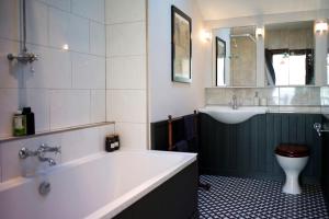 a bathroom with a tub and a toilet and a sink at The Presbytery, Forres in Forres