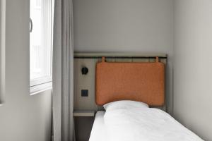 a bed with an orange headboard sitting next to a window at Comfort Hotel Børsparken in Oslo