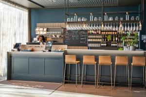 a woman sitting at a counter in a bar with stools at Comfort Hotel Børsparken in Oslo
