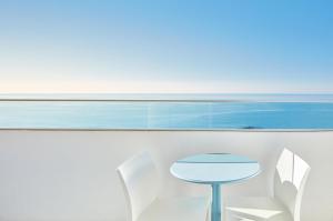 a blue table and white chairs in front of a window at Dom Jose Beach Hotel (Plus) in Quarteira