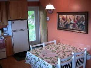 uma cozinha com uma mesa e um quadro na parede em La Source Enchantée em Baie-Saint-Paul