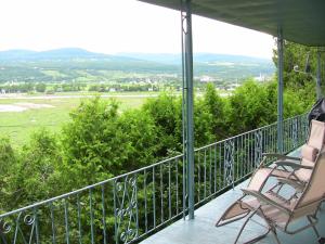 a balcony with two chairs and a view of a field at La Source Enchantée in Baie-Saint-Paul
