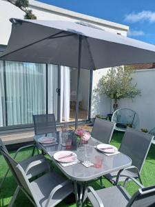 a table and chairs with an umbrella on a patio at 'The Limes' - Air-Con Two Double Bedroom Holiday House with Private Garden in Kent