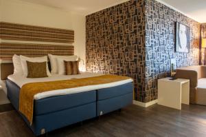 una camera con un grande letto e una sedia di Albus Hotel Amsterdam City Centre ad Amsterdam