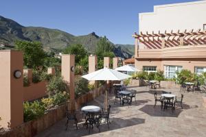 d'une terrasse avec des tables, des chaises et un parasol. dans l'établissement Hotel SPA TermaEuropa Balneario Arnedillo, à Arnedillo