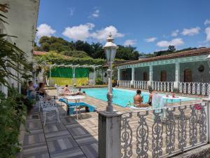 a group of people sitting around a swimming pool at Pousada do Mendonça in Juiz de Fora