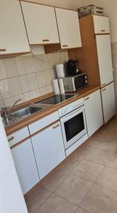 uma cozinha com armários brancos, um lavatório e um micro-ondas em Casa Dana em Tăşnad