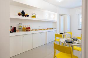 a white kitchen with yellow chairs and a table at Nesea in Piano di Sorrento