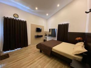 a bedroom with a bed with black curtains and a tv at RR Holidays - Home Stay in Kodaikānāl