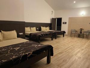 a room with three beds and a table and chairs at RR Holidays - Home Stay in Kodaikānāl