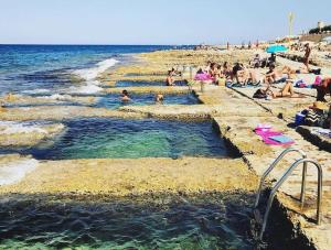 a group of people in the water at a beach at Lovely two bedroom apartment seconds from the Sea! in Sliema