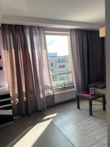 a living room with a large window and a table at Panama Apartament 3 Poznań in Poznań