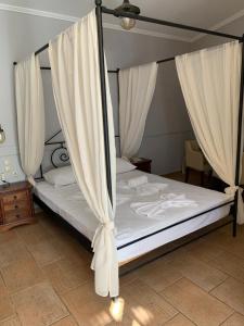 a bed with white curtains in a bedroom at Hotel Notara in Diakofti