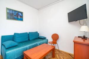 a living room with a blue couch and a flat screen tv at Apartments Peco in Mokošica