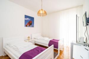 a white bedroom with two beds and a sink at Apartments Peco in Mokošica +44 photos