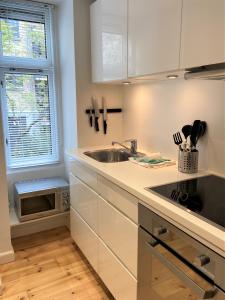 cocina con armarios blancos, fregadero y ventana en Cozy apartment in elegant Østerbro, en Copenhague