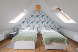 dwa łóżka w pokoju z poddaszem w obiekcie Mazurski Dom nad Jeziorem & Sauna by Downtown Apartments w mieście Tomaszkowo