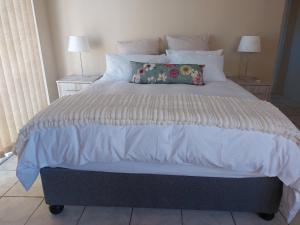 - un lit avec une couette et des oreillers blancs dans l'établissement Cenikma Guest Suites - Couples Room, à East London