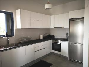 a kitchen with white cabinets and a stainless steel refrigerator at Archos Seafront Apartments in Porto Heli
