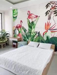 a bedroom with a white bed and a wall with birds at HOSTEL ARIA in Quy Nhon