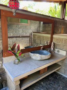 a bathroom with a stone sink and a mirror at Balian Beach Villa in Selemadeg