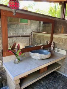 La salle de bains est pourvue d'un lavabo en pierre et d'un miroir. dans l'établissement Balian Beach Villa, à Selemadeg