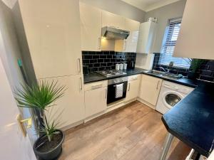a kitchen with white cabinets and a washer and dryer at Cozy Two Bedroom - A Stroll from Gardens to Beach - With Parking in Bournemouth