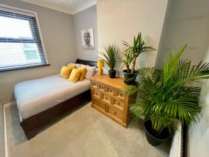 Un dormitorio con una cama con plantas. en Cozy Two Bedroom - A Stroll from Gardens to Beach - With Parking en Bournemouth