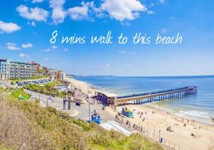 a beach with a pier and the words mins walk to this beach at Cozy Two Bedroom - A Stroll from Gardens to Beach - With Parking in Bournemouth