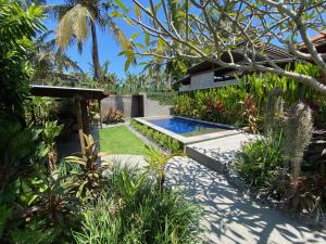 a garden with a swimming pool and a house at Balian Beach Villa in Selemadeg