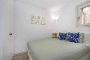 ein Schlafzimmer mit einem Bett mit blauen Kissen und einem Fenster in der Unterkunft WHome Bairro Alto 2-Bed Central Location Fully Equipped in Lissabon
