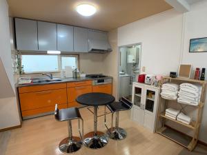 a kitchen with a table and two stools at Nagayama Home in Asahikawa