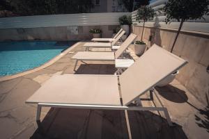 a row of picnic tables next to a swimming pool at Chrielka Hotel in Limassol