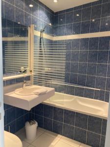 a blue tiled bathroom with a sink and a tub at Logis Hôtel Restaurant LE MONARQUE in Blois