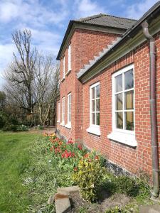 a brick house with flowers in the yard at Green vagon, farm b&b rooms for rent in Hjørring