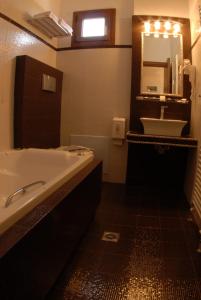 a bathroom with a tub and a sink and a mirror at Dryades Hotel in Naousa