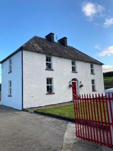a white house with a red fence in front of it at Entire Farmhouse in Tipperary in Nenagh
