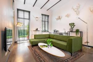 a living room with a green couch and a surfboard at Landgoed Kasteel de Hoogenweerth in Maastricht