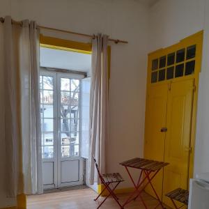 um quarto com uma porta amarela, uma mesa e uma janela em Historical da Matriz em Loulé