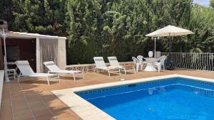 a swimming pool with chairs and an umbrella next to it at Villa Mis 5 Amores con piscina in Benidorm