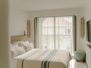 a bedroom with a bed and a large window at Hôtel & Spa Belle Plage in Cannes