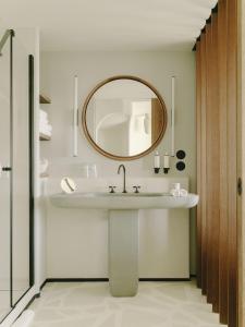 a bathroom with a sink, mirror, and bathtub at Hôtel Belle Plage in Cannes